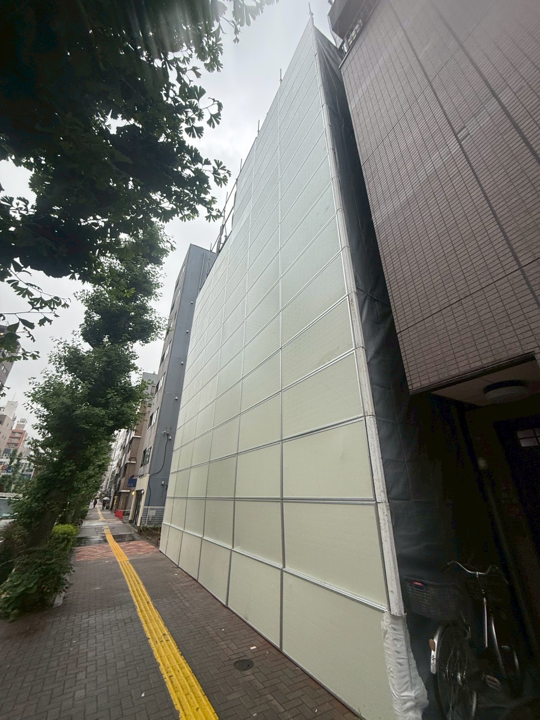 ビル解体工事で建物全体を覆った防音パネルを歩道から見た様子