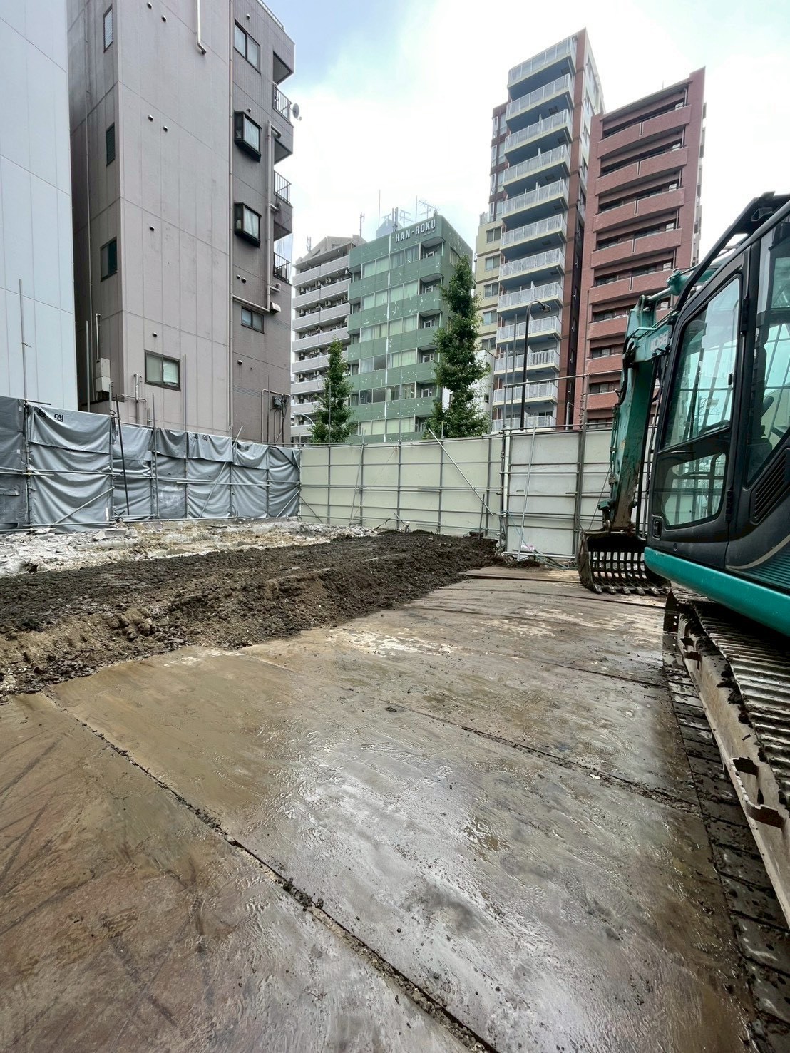 ビル解体工事の仕上げで掘削跡を埋め戻し整地している重機